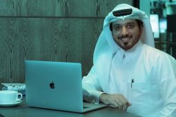 A man using a laptop while smiling.
