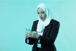  امرأة عربية تستخدم هاتفها المحمول وتبدو متفاجئة.