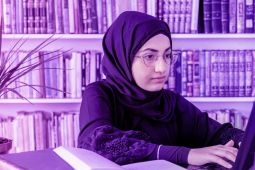 شابة ترتدي الحجاب وتكتب على الكمبيوتر المحمول.