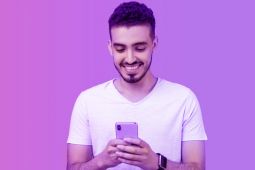 A youth using his smartphone while smiling.