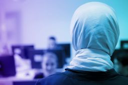 صورة من الخلف لمعلمة ترتدي الحجاب وتقف أمام طلابها.
