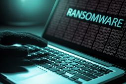 A hand of a cyber attacker on a laptop showing the word Ransomware.